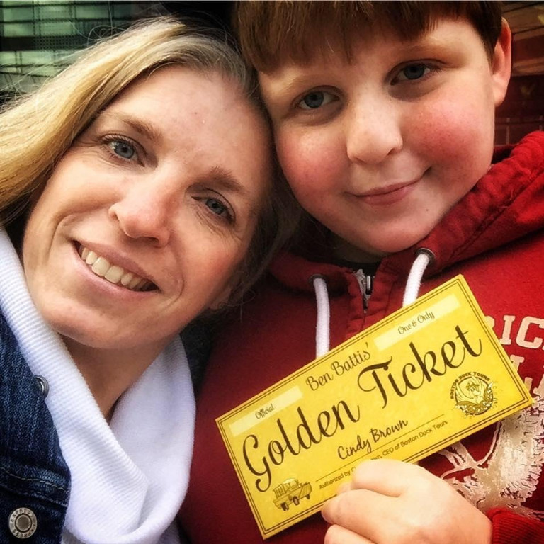 a boy holding up a golden ticket next to his mom