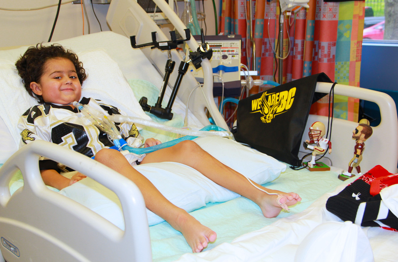 a boy smiling while lying in a hospital bed