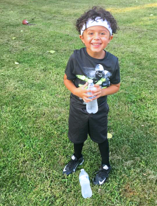 a boy in athletic clothing and headband smiling