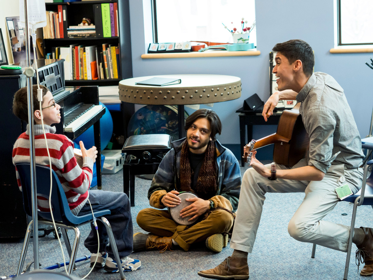 a boy playing music with two teachers