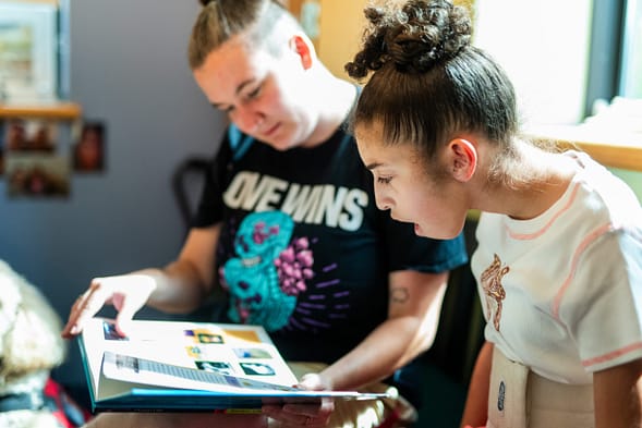 a woman helping a teenage girl read a book