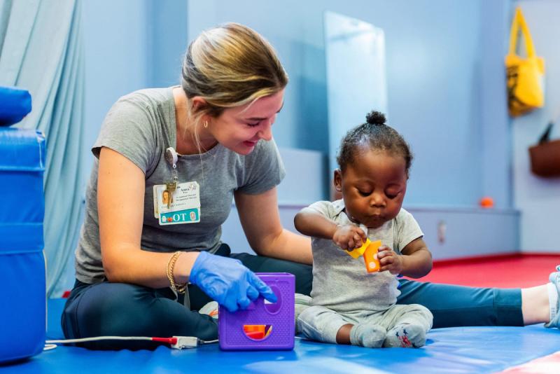 a female medical provider helping a young girl play with blocks