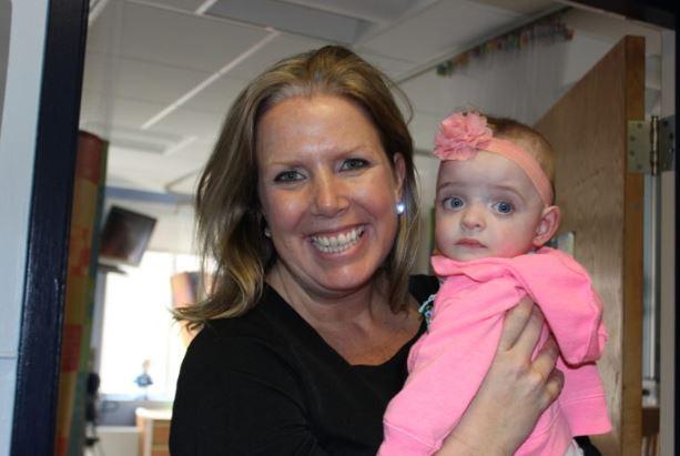 a woman smiling while holding a newborn girl