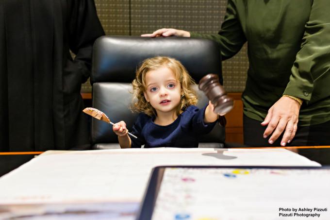 a young girl sitting in a judges chair holding a gavel