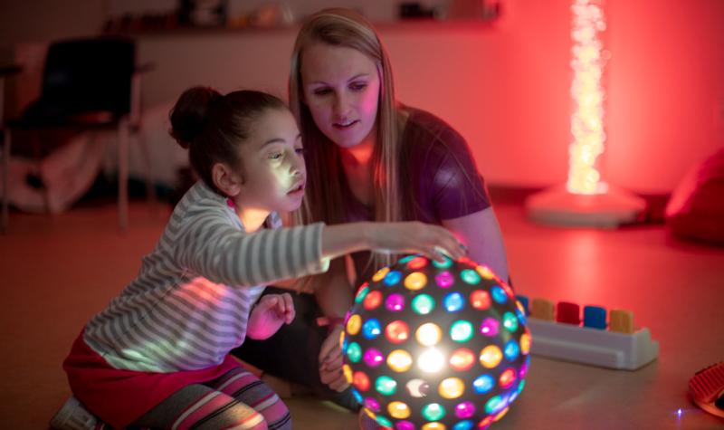 a girl playing with a colorful discoball with a woman medical provider next to her
