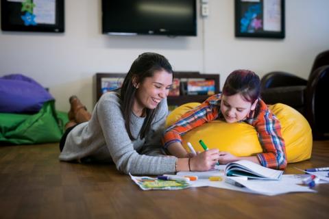 a girl on a beanbag chair drawing with a woman helping her